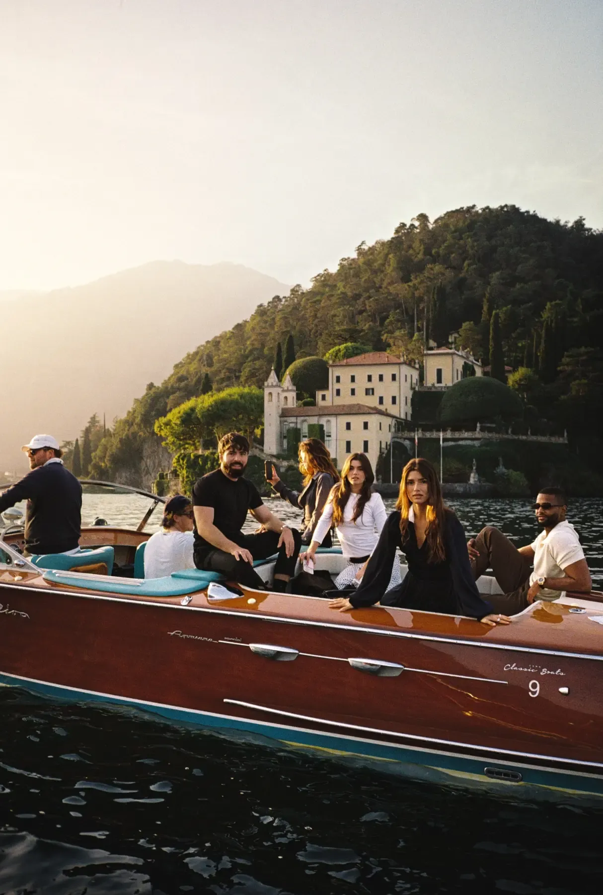 Guests arriving by classic wooden boat on Lake Como at golden hour